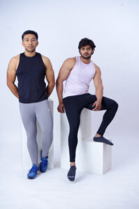 Two men, one sitting and one standing wearing compressor training tights, with Sweat Wicking capability activewear.